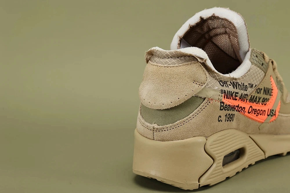 Off-White x Air Max 90 Desert Ore - Three-Quarter Lateral View of Both Shoes on Olive Background Showing Full Tonal Desert Ore Construction Hot Coral Swoosh Teal Zip-Tie and White NIKE SPORTSWEAR Tongue Label