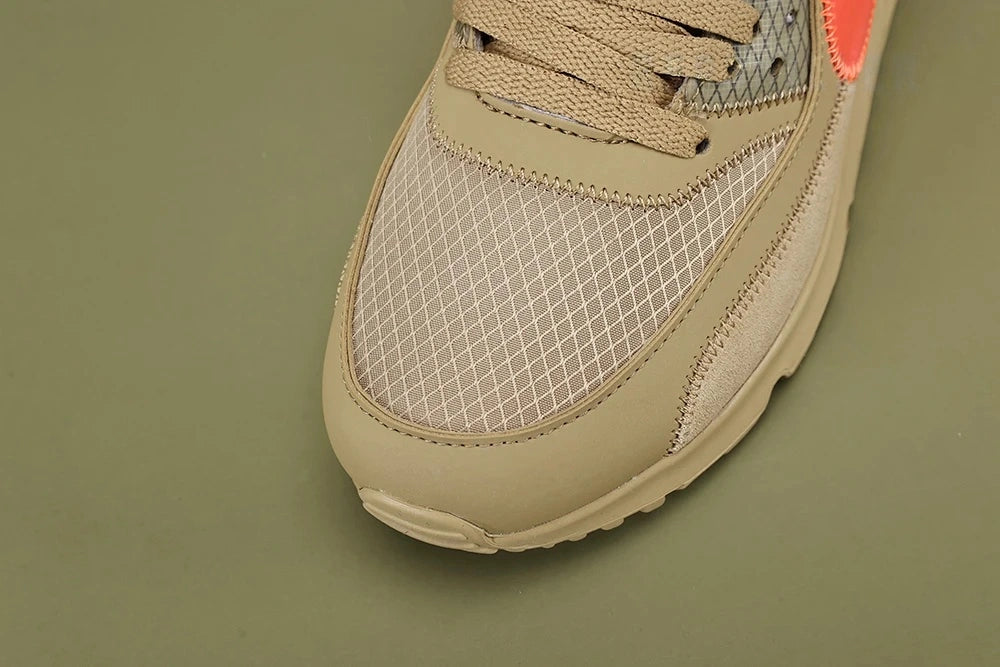 Off-White x Air Max 90 Desert Ore - Rear Heel View of Both Shoes on Olive Background Showing Sand Suede Heel Counter Raw Edges Tonal Sand Midsole and Additional Hot Coral Rope Laces in Plastic Bag Attached to Heel