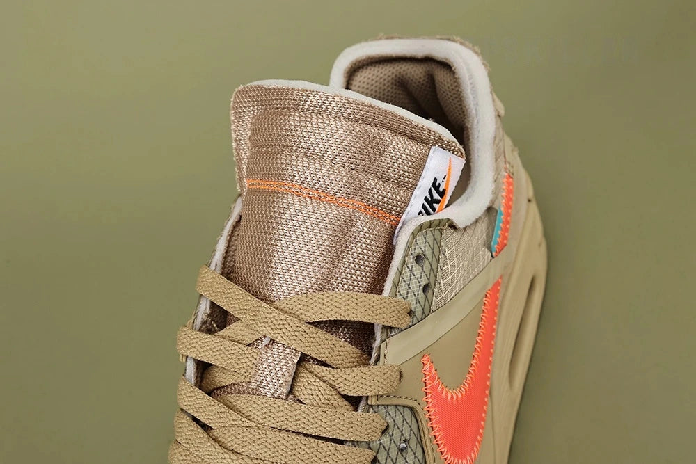 Off-White x Air Max 90 Desert Ore - Outsole View on Olive Background Showing Full Sand Desert Ore AM90 Rubber Outsole with Square-Block and Wave-Pattern Traction Debossed NIKE Text at Midfoot and Teal Zip-Tie Visible at Heel