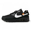 Off-White x Air Max 90 Black - Three-Quarter Lateral View of Both Shoes on Olive Background Showing Triple Black Upper White Raw-Edge Swoosh Orange Zip-Tie and Light Blue Heel Zip-Tie with White Laces Bag