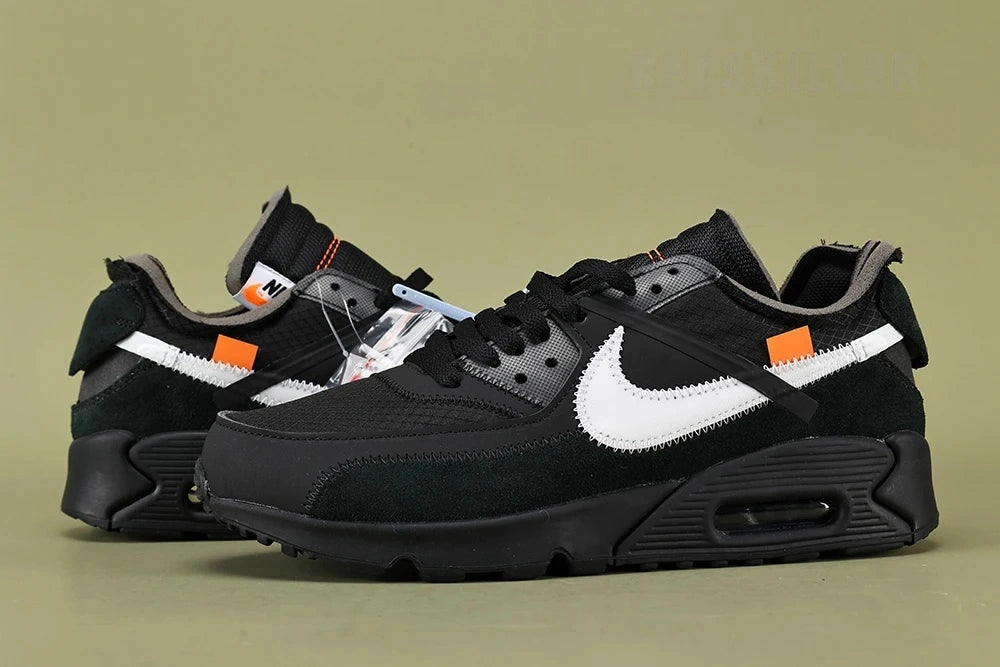 Off-White x Air Max 90 Black - Outsole View on Olive Background Showing Full Black AM90 Rubber Outsole with Square-Block and Wave-Pattern Traction and Orange Square Tab Visible at Tongue
