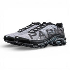 Paris Saint-Germain x Air Max Plus Black Particle Grey - Full Lateral Profile View on Dark Background Showing Black Patent Leather TN Upper Particle Grey Hex Mesh with Black PSG Lettering Black Mini Swoosh and Yellow Tn AIR Heel Badge