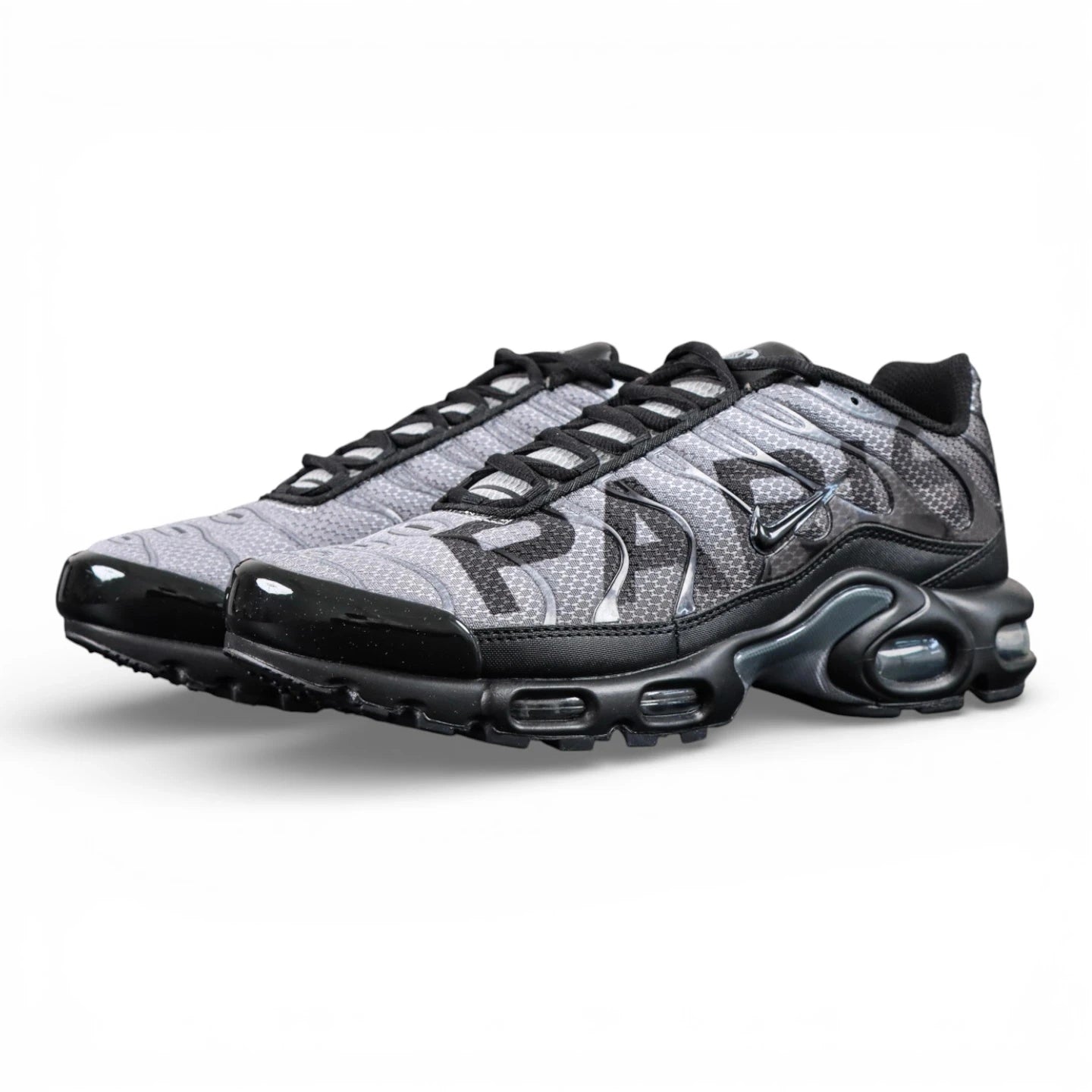Paris Saint-Germain x Air Max Plus Black Particle Grey - Full Lateral Profile View on Dark Background Showing Black Patent Leather TN Upper Particle Grey Hex Mesh with Black PSG Lettering Black Mini Swoosh and Yellow Tn AIR Heel Badge