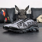 Paris Saint-Germain x Air Max Plus Black Particle Grey - Tongue and Ankle Collar Top Down View on Dark Background Showing Circular PSG Badge with White Ground Black PARIS SAINT-GERMAIN Text and PSG Trident Crest on Medial Tongue Panel