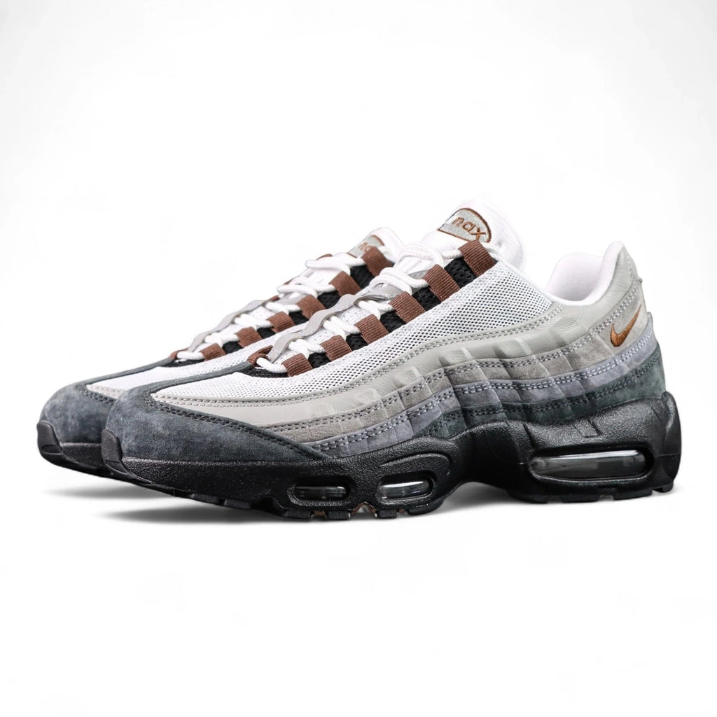 SB x Air Max 95 Cacao Wow 2026 - Lateral Profile and Outsole View on Dark Background Showing White Grey Gradient Vintage Suede AM95 Upper Cacao Wow Brown Mini Swoosh Brown Grosgrain Ribbon Lace Tabs and Black Brown Herringbone Outsole