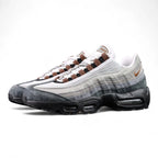SB x Air Max 95 Cacao Wow 2026 - Lateral Profile and Outsole View on Dark Background Showing White Grey Gradient Vintage Suede AM95 Upper Cacao Wow Brown Mini Swoosh Brown Grosgrain Ribbon Lace Tabs and Black Brown Herringbone Outsole