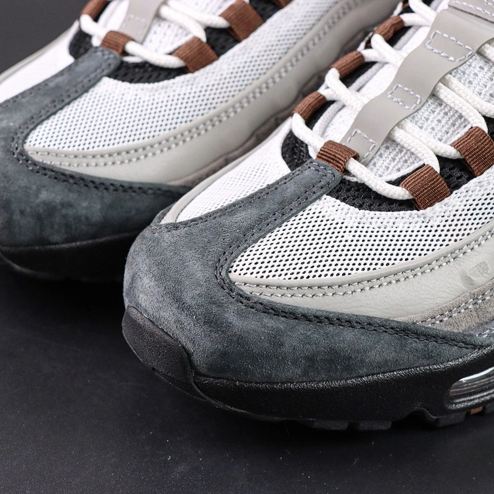 SB x Air Max 95 Cacao Wow 2026 - Three-Quarter Lateral View with Purple Shoebox on Dark Background Showing White Grey Gradient Suede AM95 Upper Brown Grosgrain Ribbon Lace Tabs and Cacao Wow Mini Swoosh