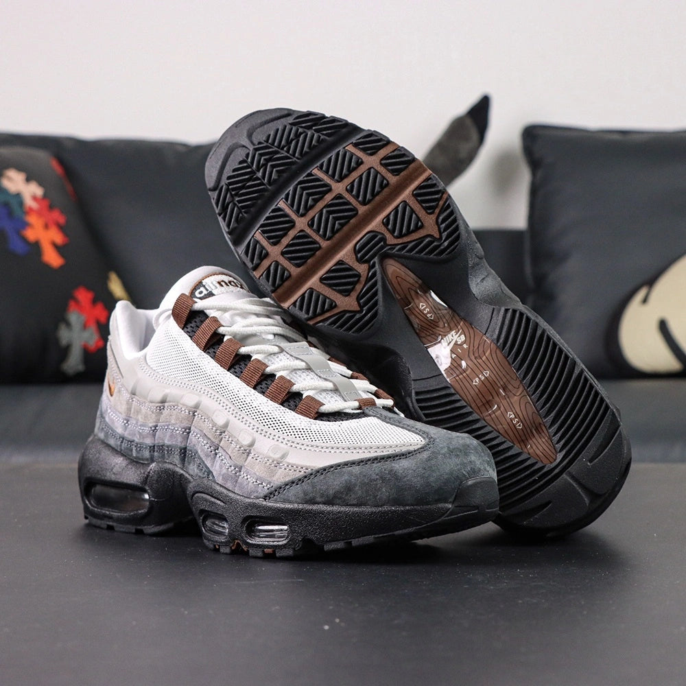 SB x Air Max 95 Cacao Wow 2026 - Top Down View of Both Shoes on Dark Background Showing SB x AM95 Oval Tongue Badge with White Ground Cacao Wow Brown Embroidered Air Max Script and Brown Grosgrain Ribbon Lace Tabs