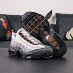 SB x Air Max 95 Cacao Wow 2026 - Top Down View of Both Shoes on Dark Background Showing SB x AM95 Oval Tongue Badge with White Ground Cacao Wow Brown Embroidered Air Max Script and Brown Grosgrain Ribbon Lace Tabs