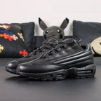 Supreme x Air Max 95 Lux Black - Rear Heel View of Both Shoes on Dark Background with Pikachu Plush Showing Full Black Leather Heel Counter AM95 Spine Overlays and Dark-Tinted AM95 Air Unit at Heel