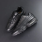 Supreme x Air Max 95 Lux Black - Rear Heel View of Both Shoes on Dark Background Showing Black Leather AM95 Heel Counter Spine Overlays and Dark-Tinted AM95 Air Unit