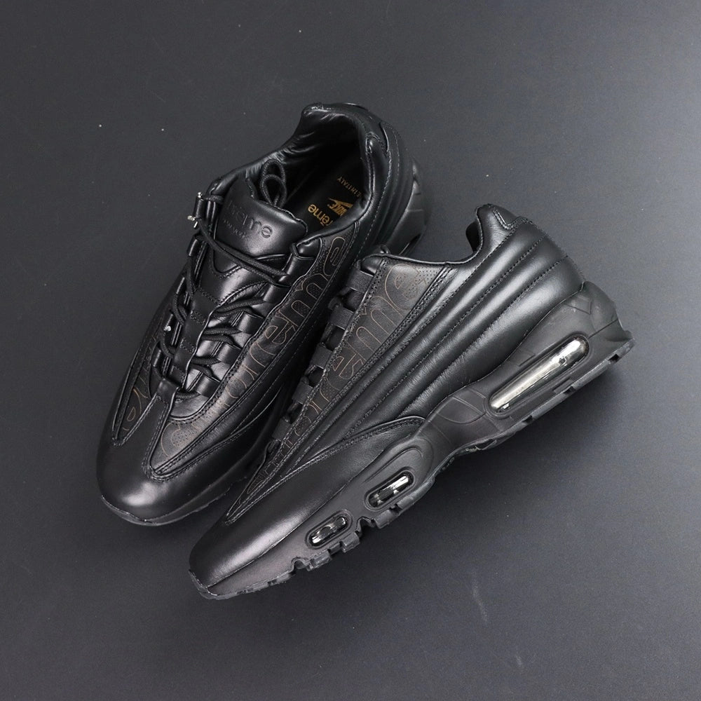 Supreme x Air Max 95 Lux Black - Rear Heel View of Both Shoes on Dark Background Showing Black Leather AM95 Heel Counter Spine Overlays and Dark-Tinted AM95 Air Unit