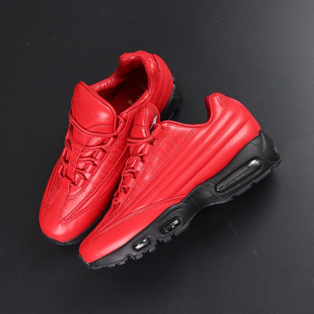 Supreme x Air Max 95 Lux Gym Red - Rear Heel View of Both Shoes on Dark Background Showing Quilted Diamond-Stitch Gym Red Leather Heel Collar Black Metal Ball-Chain Dubrae and Full Black AM95 Midsole with Dark-Tinted Air Unit