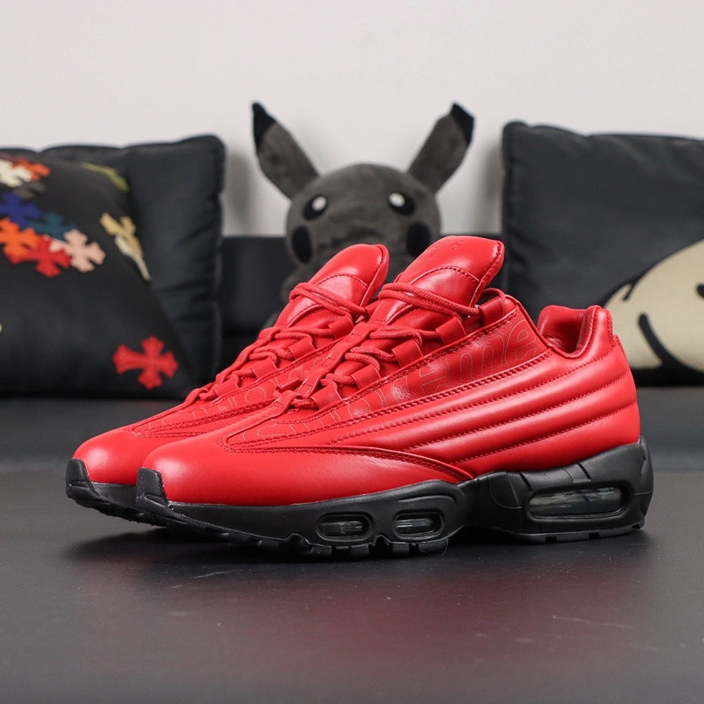 Supreme x Air Max 95 Lux Gym Red - Toe Box Close Up on Dark Background Showing Premium Gym Red Smooth Leather Toe Box Tone-on-Tone Supreme Cursive Script Debossed on Red Leather Quarter Panel and Black Midsole Edge