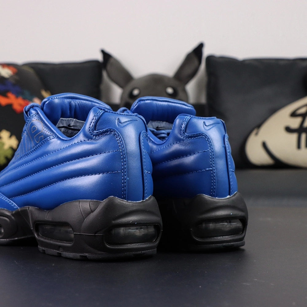 Supreme x Air Max 95 Lux Hyper Cobalt - Lateral Profile View on Dark Background with Pikachu Plush Showing Hyper Cobalt Blue Leather AM95 Spine Overlays Tone-on-Tone Supreme Script and Full Black Midsole