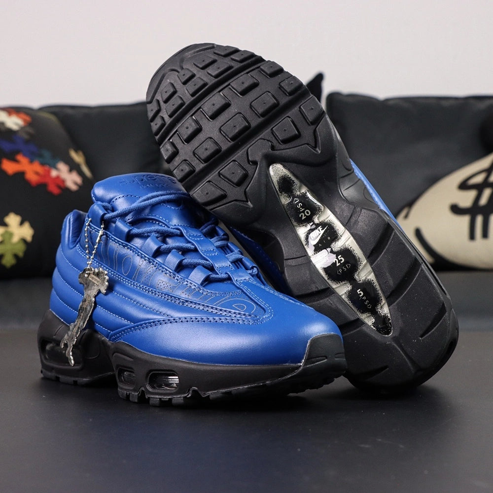 Supreme x Air Max 95 Lux Hyper Cobalt - Three-Quarter Top View of Both Shoes on Dark Background Showing Full Hyper Cobalt Blue Leather AM95 Upper Tone-on-Tone Supreme New York Cursive Script on Both Lateral and Medial Panels and Blue Rope Laces