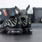 Swarovski x Air Max Plus Moonlight 2024 - Full Lateral Profile View with Pikachu Plush on Dark Background Showing Complete Triple Black TN Upper with Swarovski Crystal Rhinestone Wave-Form Lines and Crystal Swoosh on Lateral Midfoot