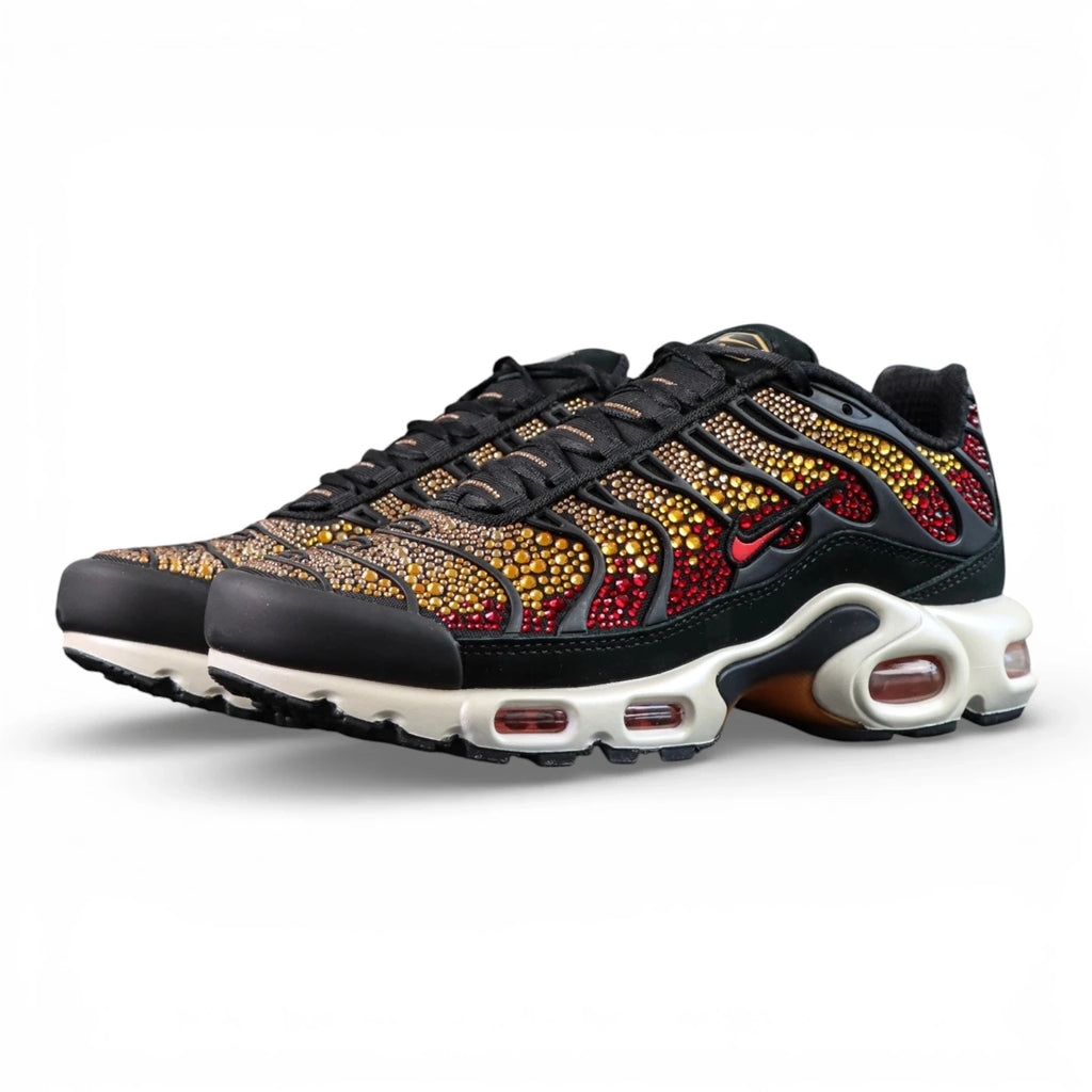 Swarovski x Air Max Plus Sunset - Lateral Profile and Outsole View on Dark Background Showing Black TN Upper with Swarovski Crimson to Gold Sunset Crystal Gradient and Tri-Colour Outsole with Black Rubber Red Triangular Traction Blocks and Orange Underlayer
