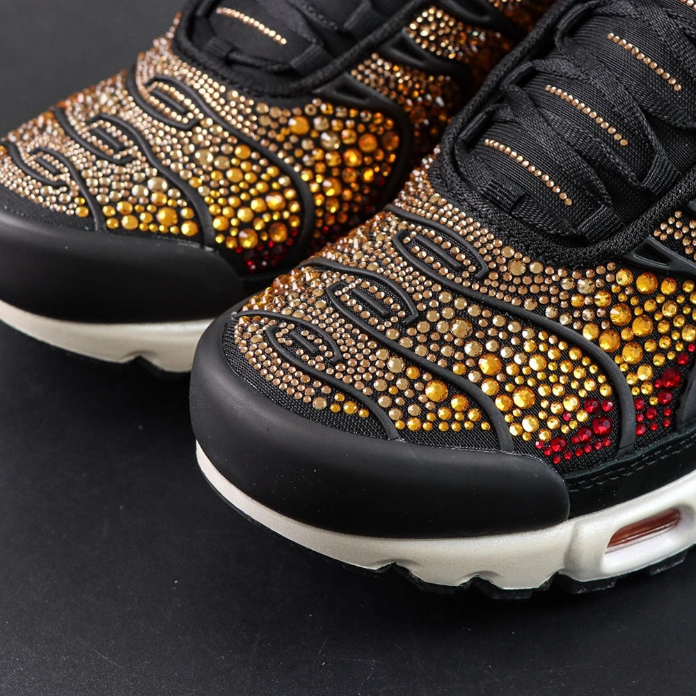 Swarovski x Air Max Plus Sunset - Three-Quarter Top View of Both Shoes on Dark Background Showing Full Swarovski Crimson to Amber to Gold Sunset Crystal Gradient Across TN Wave-Form Spine Overlay Panels and Red Swoosh on Lateral Midfoot