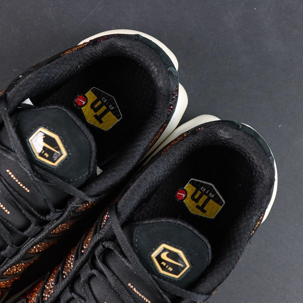 Swarovski x Air Max Plus Sunset - Full Lateral Profile View with Pikachu Plush on Dark Background Showing Complete Swarovski Sunset Crystal Gradient from Deep Crimson at Heel to Bright Gold at Toe Box and White Midsole with Amber Air Units