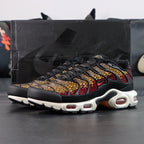 Swarovski x Air Max Plus Sunset - Three-Quarter Lateral View with Pikachu Plush on Dark Background Showing Swarovski Crimson to Gold Crystal Gradient Across TN Wave-Form Panels Red Swoosh and White Midsole with Amber-Tinted TN Air Units