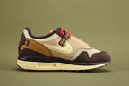 Air Max 1 Cactus Jack Baroque Brown Wheat Cream University Red - Lace Area Close Up on Olive Background Showing Cream Circular Lace Lock with Cream Logo Badge Black Multicolour Stripe Woven Webbing Lace Loops University Red White-Speckle Rope Laces Wheat Quarter Panel and University Red Collar Lining