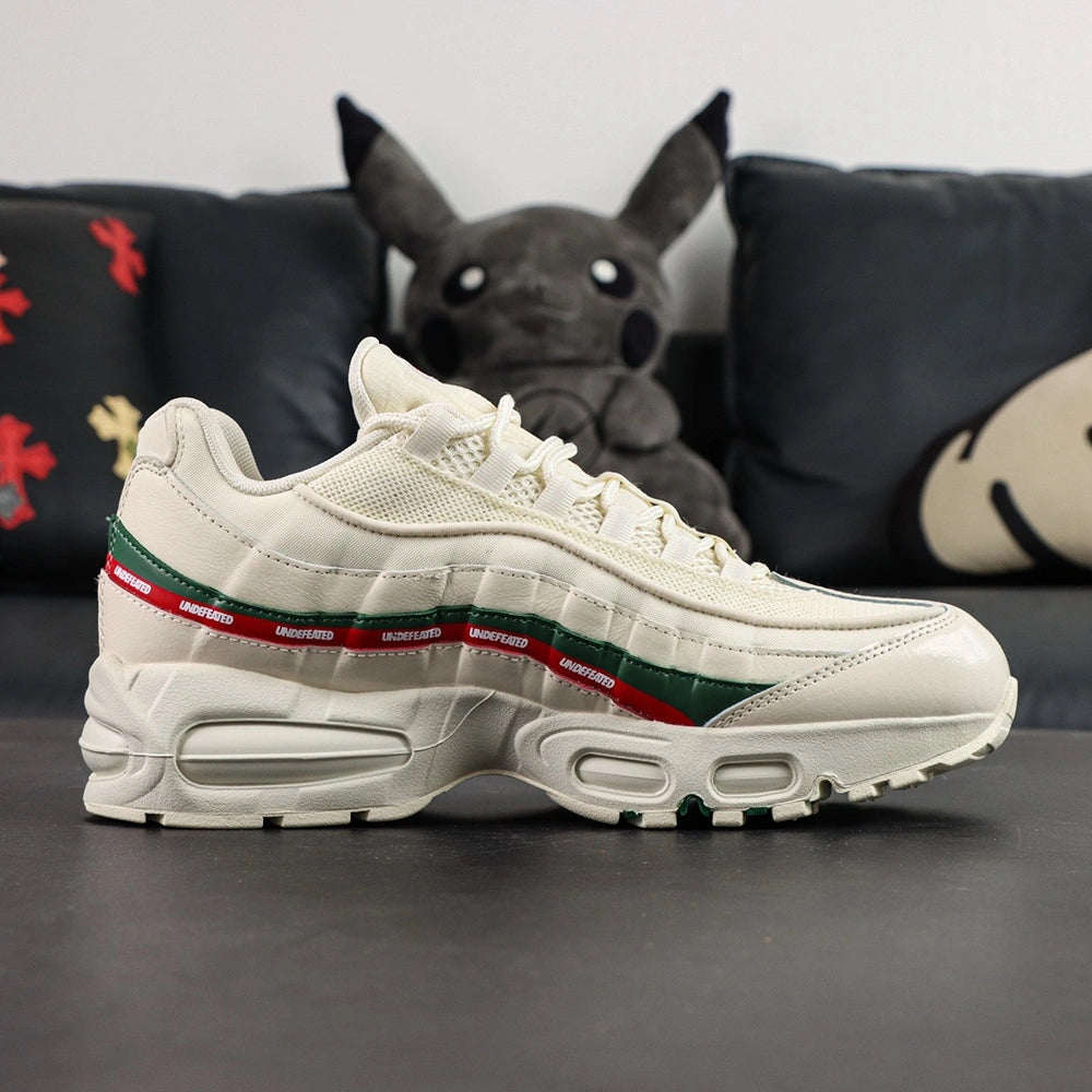 Undefeated x Air Max 95 Sail 2025 - Tongue and Insole Top Down View on Dark Background Showing Sail Tongue with Green NK AIR Text Red Air Max Oval Badge and Black Undefeated Five-Strike Logo on Sail Insole