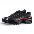 Undefeated x Air Max 95 Black 2025 - Three-Quarter Lateral Top View of Both Shoes on Dark Background Showing Triple Black Patent Leather Mesh and Crinkled Leather AM95 Upper Dark Green Leather Spine Stripe and Red UNDEFEATED Repeat-Text Ribbon
