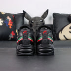 Undefeated x Air Max 95 Black 2025 - Lateral Profile and Outsole View with Pikachu Plush on Dark Background Showing Triple Black AM95 Upper Green and Red UNDEFEATED Dual Stripe and Black Outsole with Full Red Square-Block Traction Grid and Green GET THE FUCK OUT Text on Outsole Heel
