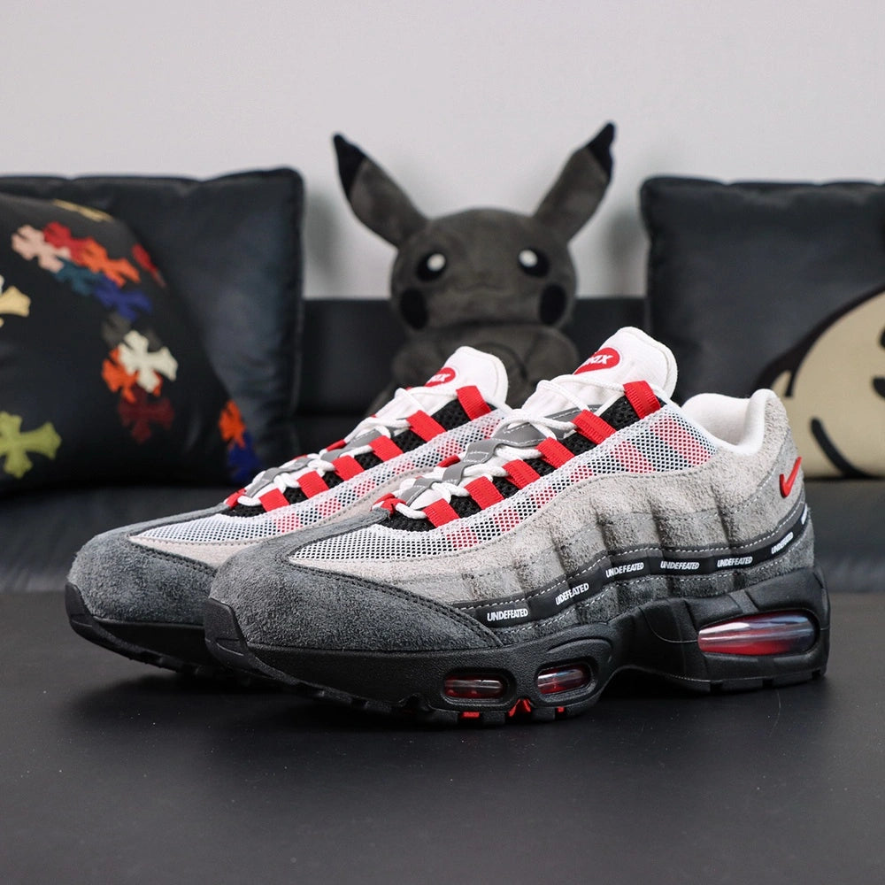 Undefeated x Air Max 95 Bright Crimson 2025 - Tongue and Ankle Collar Top Down View on Dark Background Showing White Tongue with Red Air Max Oval Badge Red Textile Ankle Collar Lining with Black Undefeated Five-Strike Logo and Red Lace Aglets