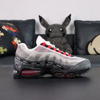 Undefeated x Air Max 95 Bright Crimson 2025 - Toe Box Close Up on Dark Background Showing Dark Grey Suede AM95 Toe Box White Large-Hole Mesh Quarter Panel with Red Mesh Underlayer and Black UNDEFEATED Ribbon Segments on Spine Divider Lines
