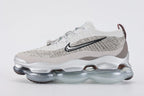 Air Max Scorpion Flyknit Gaiter Light Bone Metallic Silver - Toe Box and Lateral Midfoot Close Up on Grey Background Showing Light Bone Perforated Suede Overlay with Dense Small-Circle Perforation Pattern Heathered Flyknit Upper Black Filled Swoosh Embroidery and Metallic Silver AM Scorpion Air Unit at Forefoot with Dark Brown Traction Pods