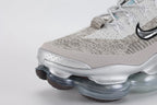 Air Max Scorpion Flyknit Gaiter Light Bone Metallic Silver - Heel Counter Close Up on Grey Background Showing Integrated Smoky Mauve Terry Cloth Gaiter Covering Full Heel Collar Powder Blue Perforated Rectangular Badge at Gaiter Top and Metallic Silver AM Scorpion Air Unit at Heel