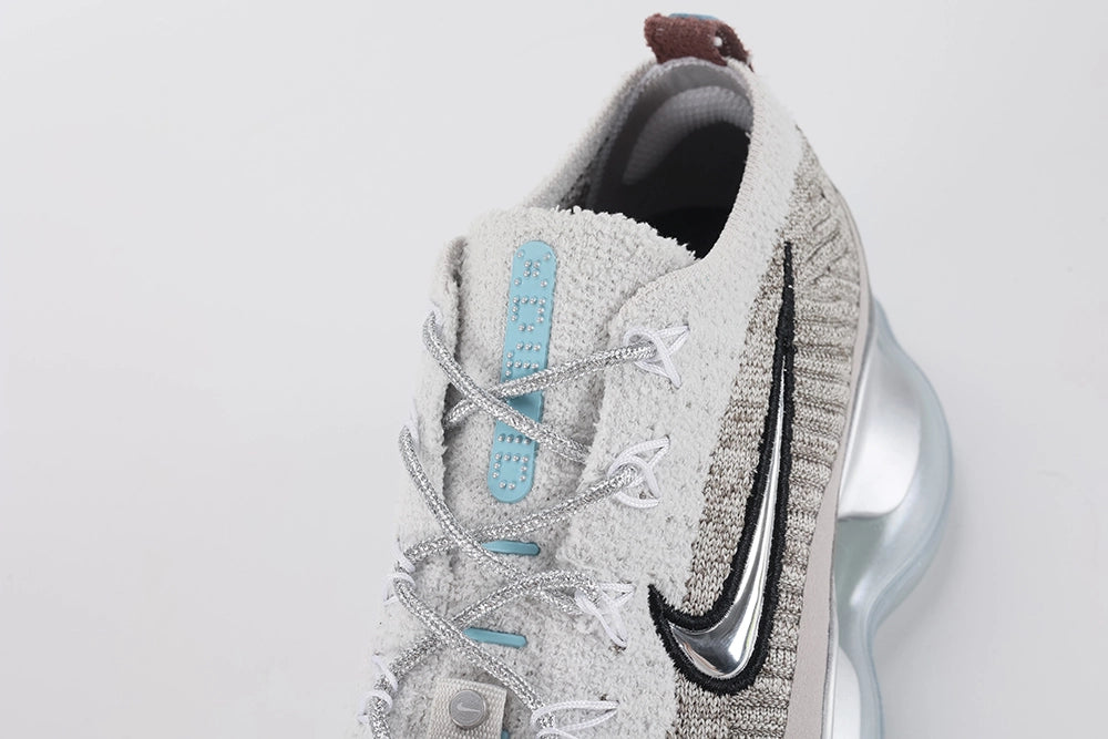 Air Max Scorpion Flyknit Gaiter Light Bone Metallic Silver - Rear View of Both Shoes on Grey Background Showing Integrated Smoky Mauve Terry Cloth Gaiter at Heel Collar Powder Blue Perforated Badge at Gaiter Top Silver Metallic Mini Swoosh on Midsole Heel Counter and Large-Volume Metallic Silver AM Scorpion Air Unit with Dark Brown Traction Pods