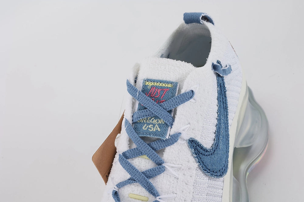 Air Max Scorpion Flyknit Just Do It White Diffused Blue - Heel Counter Close Up on White Background Showing Teal and Pink Dragonfly Embroidery Diffused Blue Terry Heel Pull Tab with Black JUST DO IT Text and Frosted Grey AM Scorpion Air Unit with Multicolour Iridescent Outsole at Heel