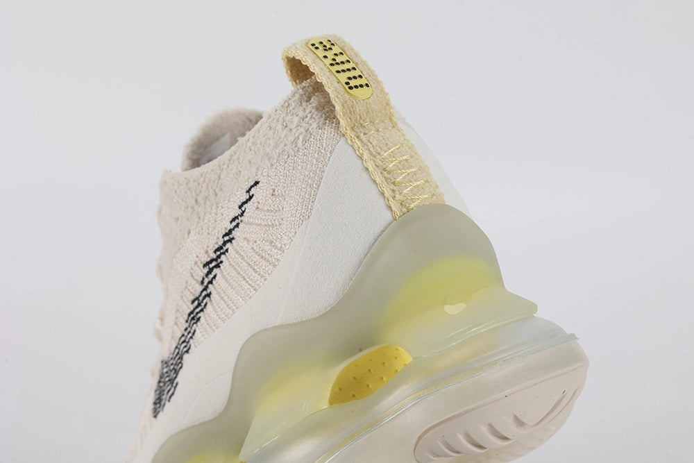 Air Max Scorpion Flyknit Lemon Wash Light Orewood Brown Lemon Chiffon - Lace Area Close Up on White Background Showing Silver Oval Lace Keepers with Black Dot-Grid Texture Tonal Off-White Flat Laces Black Sketch-Outline Swoosh on Lateral Midfoot Boucle Flyknit Upper with Silver Metallic Thread and Lemon Chiffon Heel Pull Tab