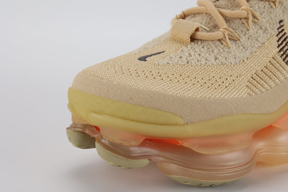 Air Max Scorpion Flyknit Sesame Dark Driftwood Total Orange - Lace Area and Tongue Close Up on White Background Showing Sesame Terry Loop-Pile Flyknit Quarter Panel Dark Driftwood Sketch-Outline Swoosh Sesame Rope Laces Sesame Lace Keeper with Dark Driftwood Dot-Grid Texture and Tan Kraft Paper Hang Tag