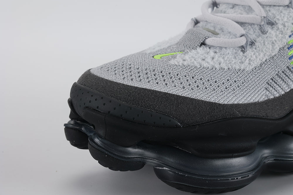 Air Max Scorpion Flyknit Wolf Grey Volt Racer Blue Black - Toe Box Top Down View on Grey Background Showing Wolf Grey Fine-Knit Flyknit Toe Box Volt Mini Swoosh Dark Grey Perforated Suede Overlay White Flat Laces and Volt and Racer Blue Knit Stripes on Lateral Midfoot Flyknit