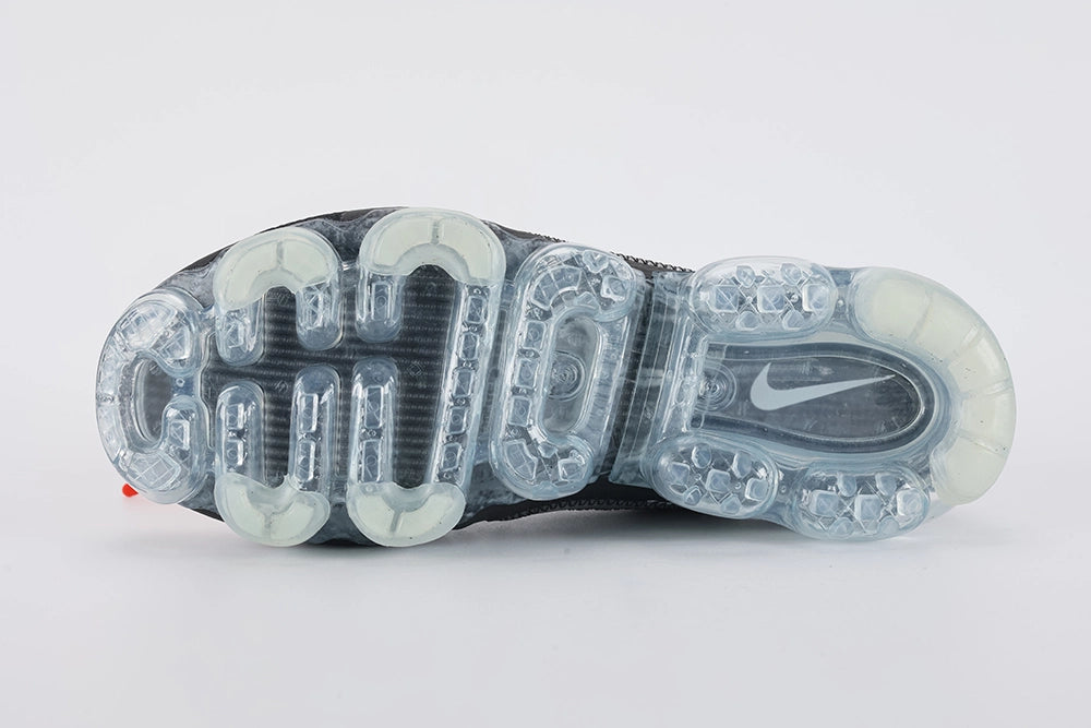 Air VaporMax co-branded Part 2 Black White Orange - Heel Counter Close Up on White Background Showing Black Woven Heel Pull Tab with Orange Rectangular Accent at Top White AIR Quotation-Mark Text at Heel Midsole Junction VAPORMAX Text on Heel Collar White Co-Branded Text System at Heel Counter and Frosted Ice VaporMax Air Unit at Heel