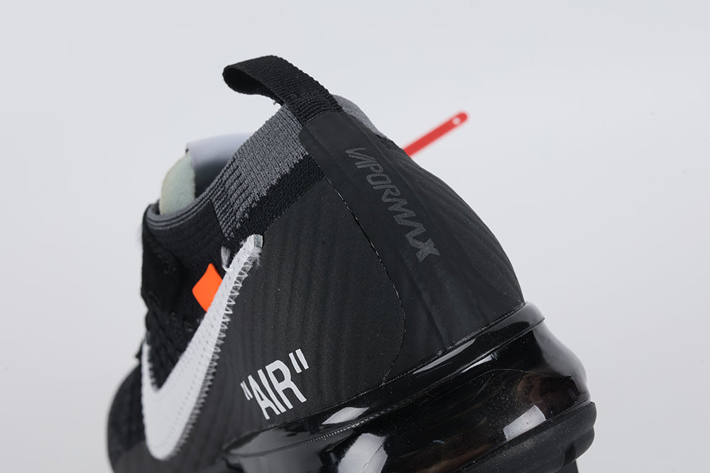 Air VaporMax co-branded The Ten Black White Red - Tongue and Lace Area Close Up on White Background Showing White Rectangular Woven Tongue Label with Black Co-Branded Sportswear Text and Orange Swoosh Red Industrial Zip Tie White Flat Laces and Black Fine-Knit Flyknit Upper